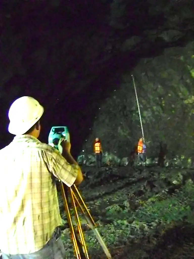 Topógrafo con estación total y brigada con baliza en el frente de los túneles de desvío del río Grijalva